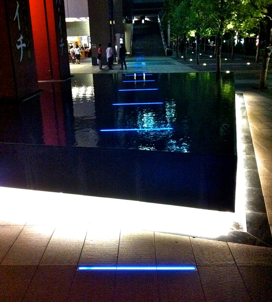 Blue neon lines art piece in Akihabara sidewalk and fountain