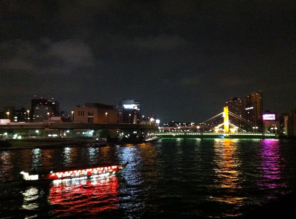 Sumida River bridge lit up at night with a pleasure boat